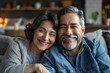 Happy mature mexican american husband and wife sit rest on couch at home hugging and cuddling, show care affection, smiling senior loving couple relax on sofa have fun, enjoy tender romantic family we