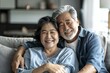 © JAYDESIGNZ - Happy mature asian husband and wife sit rest on couch at home hugging and cuddling, show care affection, smiling senior loving couple relax on sofa have fun, enjoy tender romantic family weekend toget