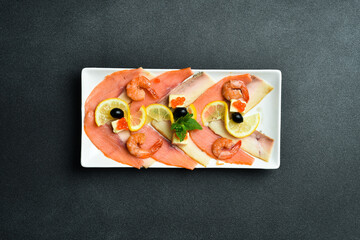 Wall Mural - Salted salmon, shrimp and caviar with butter and lemon. Appetizer. On a dark stone background. Free space for text.