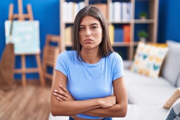 Poster - Brunette young woman sitting on the sofa at home skeptic and nervous, disapproving expression on face with crossed arms. negative person.