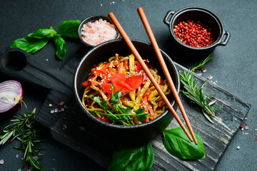 Wall Mural - Udon pasta with vegetables and ginger. In a black plate. Japanese cuisine. On a dark background, close-up.