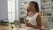 © Krakenimages.com - African american woman with curly hair on phone call holding coffee in office