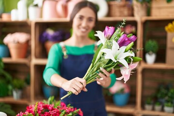 Poster - Young beautiful hispanic woman florist holding bouquet of flowers at flower shop