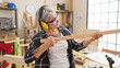 © Krakenimages.com - Serious, grey-haired middle age woman carpenter deeply invested in her woodwork, fervently looking at a timber plank in her homely carpentry workshop