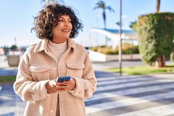 Wall Mural - Young beautiful hispanic woman smiling confident using smartphone at street