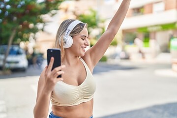 Sticker - Young blonde woman listening to music and dancing at street