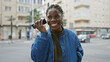 A cheerful african american woman with braids talking on a phone in a vibrant urban street setting