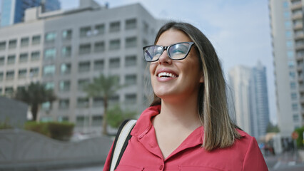 Wall Mural - Smiling woman with glasses enjoying modern cityscape on a sunny day in dubai.