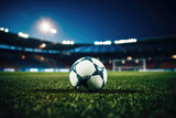 Fototapeta Sport - Black and white soccer ball on green grass in the center of a stadium, illuminated by spotlights