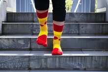 Person Walking Up Stairs, Alternating Red And Yellow Socks On Each Step