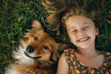 Fototapeta Dinusie - Happy kid girl and dog lying on the fresh green grass, top view. AI generative