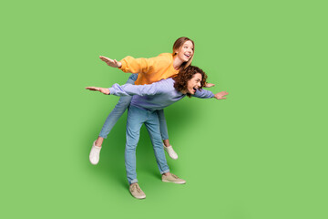 Sticker - Full body profile portrait of excited cheerful people piggyback arms wings fly empty space isolated on green color background