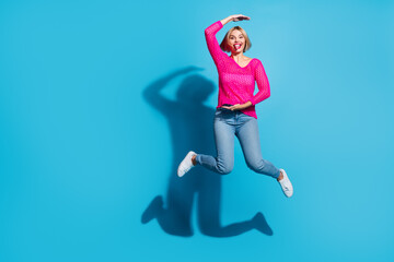 Wall Mural - Full body photo of attractive young woman jump show size measure dressed stylish pink knitted clothes isolated on blue color background