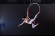 © New Africa - Young woman performing acrobatic element on aerial ring indoors
