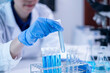 © Supapich - Closeup female woman scientist's hand holding blue liquid chemical chemistry test tube working in analyze science laboratory research experiment