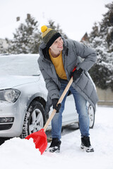 Wall Mural - Man removing snow with shovel near car outdoors