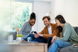 © PhotoAlto - Small group of friends gathered in living room while using smart phone