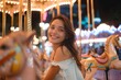 © Pinklife - A joyful woman in vibrant clothing rides a carousel horse at the fair, her beaming smile capturing the essence of pure happiness in an amusement park setting