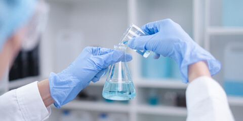 close-up hands holding pouring blue fluid liquid beaker flask test tube glassware sample laboratory 