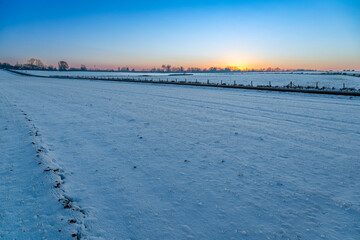 Wall Mural - Paysage d'hiver. Champ enneigé à la tombée de la nuit. Coucher de soleil