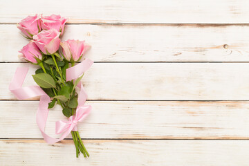 Wall Mural - Pink roses on wooden background, top view.