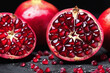Cut in half pomegranate on a black background. Detailed, close up shot. Grains of red ripe pomegranate close-up , juicy pomegranate seeds of red color