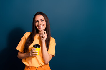 Sticker - Portrait of latin lady wear orange t shirt touch chin holding warm cacao looking empty space minded isolated on dark blue color background