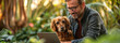 A well-groomed and smiling man with a dog Using a laptop in the garden at home