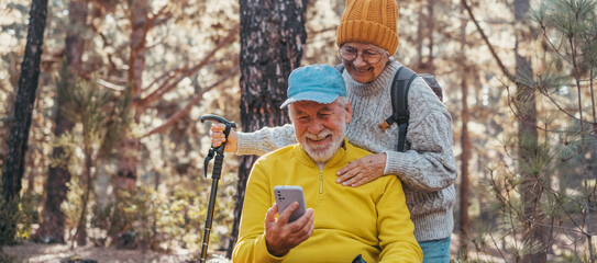 Sticker - Head shot portrait close up of couple of cute seniors using phone together in the forest with trees around them. Using cellphone mobile outdoors having fun and enjoying.