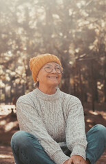 Sticker - Head shot portrait close up of one middle age old woman resting and relaxing doing yoga in the forest of mountain in the nature. One mature cheerful female person smiling enjoying..