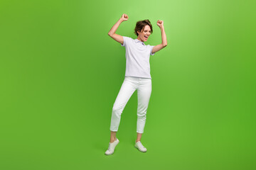 Sticker - Full length photo of cheerful lucky lady wear grey t-shirt screaming yes rising fist empty space isolated green color background