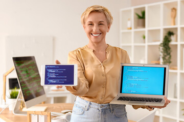 Sticker - Mature female programmer with laptop and tablet computer in office