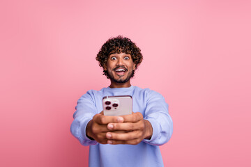 Photo portrait of attractive young man hold stare device shocked expression wear trendy blue clothes isolated on pink color background