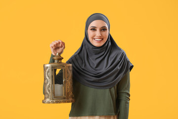 Canvas Print - Young Muslim woman with lantern on yellow background. Islamic New Year celebration