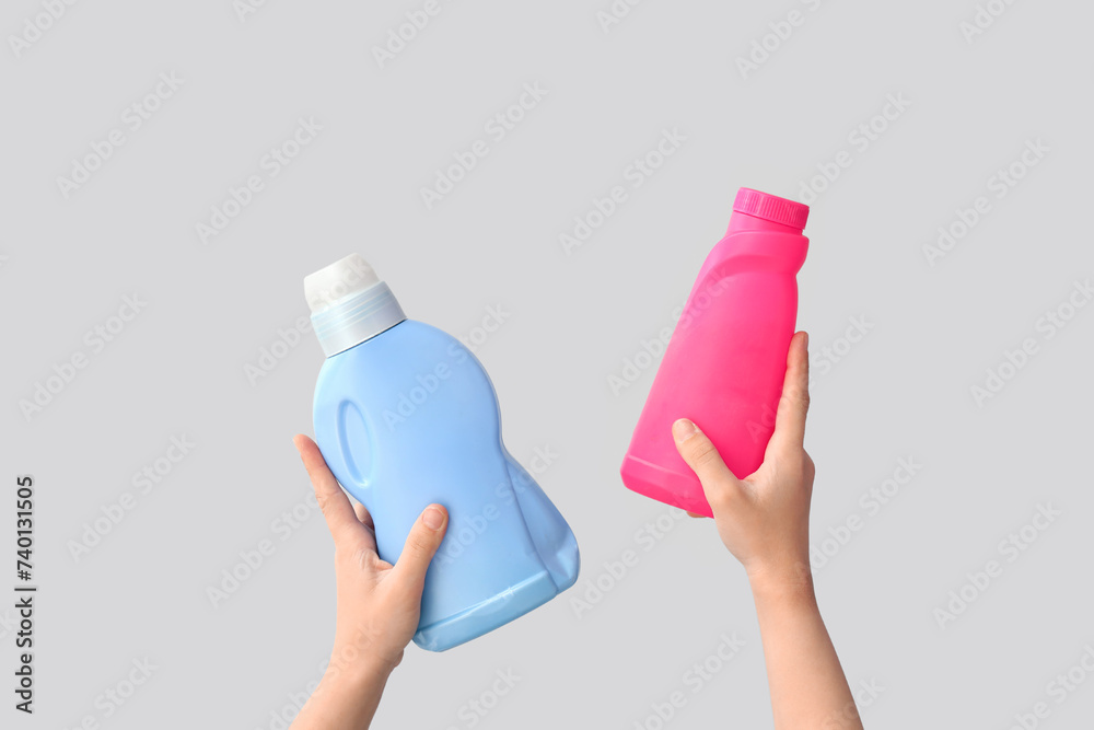 Woman with bottles of laundry detergent on light background