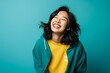 © Stocknterias - Portrait of a happy young asian woman laughing against blue background