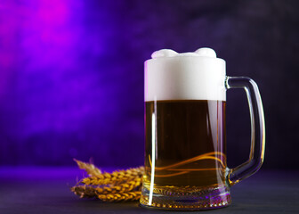 Wall Mural - Light foamy beer mug and wheat ears on a wooden table. Purple background. Copy space