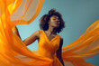 Beautiful African American woman in Mustard waving dress with flying fabric on studio background.
