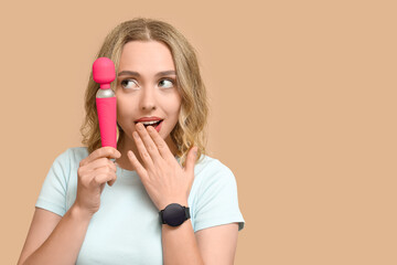 Wall Mural - Thoughtful young woman with vibrator on beige background