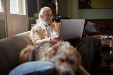 Senior Man Using Laptop On Home Sofa