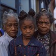 a black american girl, a middle aged black american woman and an elderly black american woman all the same person in different phases of her life. wearing the same outfit. all wearing pigtails and sam