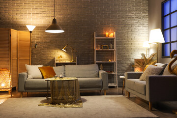 Wall Mural - Interior of stylish living room with golden decor, glowing lamps and sofas at night