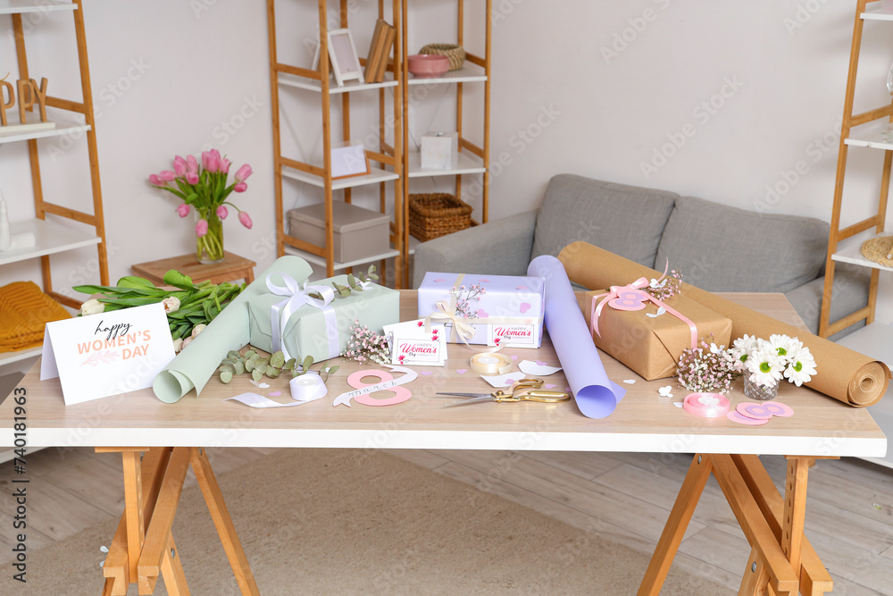 Beautiful gift boxes, packing materials and flowers on table in room