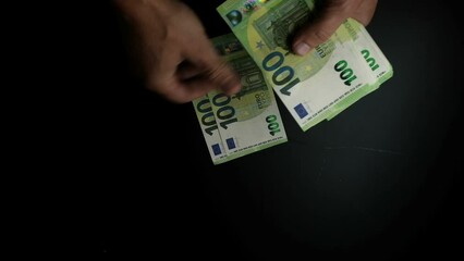 Wall Mural - Male hands counting a large stack of euro bills, close-up on a dark background