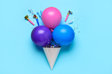 Composition with party hat, balloons and party horns on blue background