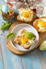 Wall Mural - Scrambled eggs in puff pastry with cheese and bacon. Easter breakfast on a festive table. Copy space.