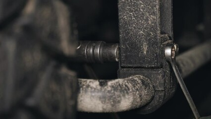 Poster - A mechanic tightens bolts with a wrench on the units and parts of a truck in a repair shop. Close-up.