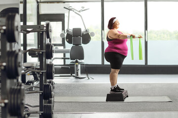 Poster - Woman exercising step aerobic with elastic band at a gym