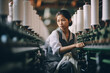 Asian young woman worker looking tired and sad while working in a textile factory because of low wages