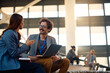 © Drazen - Happy businessman talking to female colleague while using laptop in convention center.